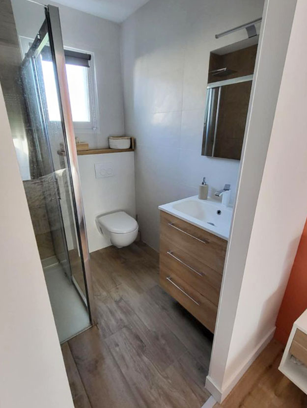 Salle de bain attenante à la suite parentale à Berchères-la-Maingot, aménagée par ABL Intérieur avec douche vitrée, WC suspendu et meuble vasque en bois.