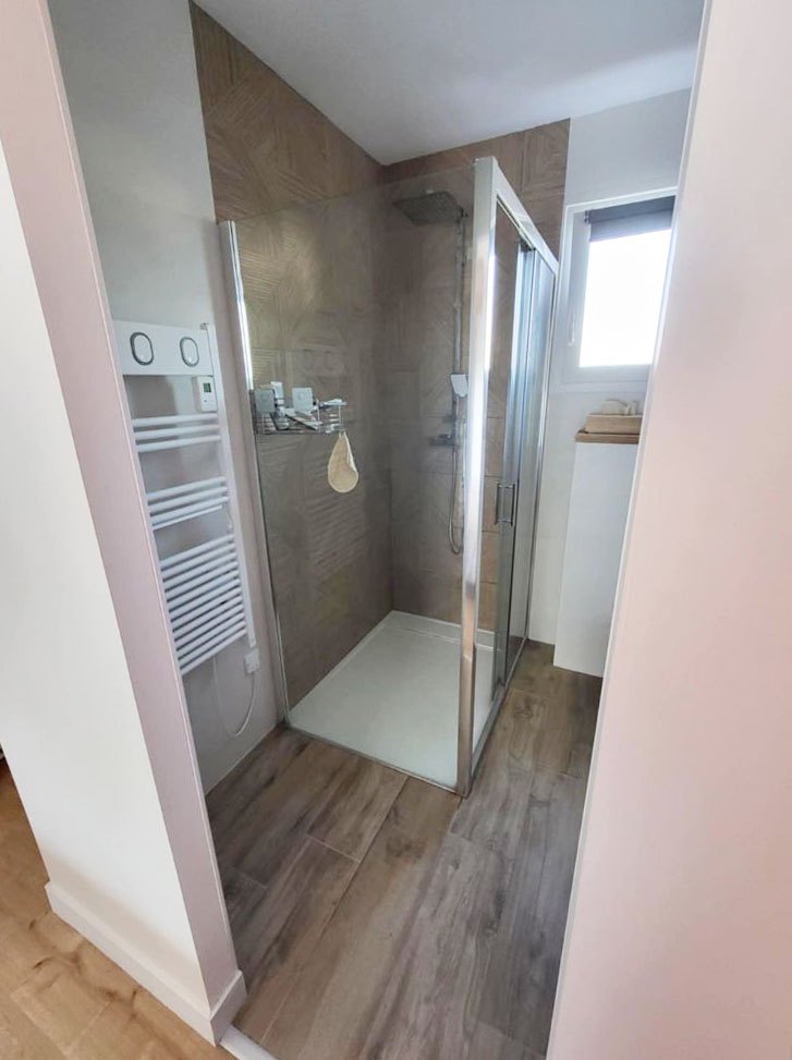Douche moderne avec parois vitrées et carrelage effet bois, conçue par ABL Intérieur à Berchères-la-Maingot.